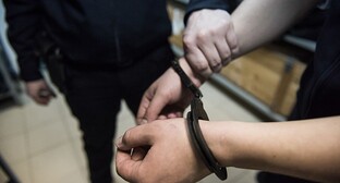 Сотрудник полиции держит за руку задержанного. Фото Елены Синеок, Юга.ру